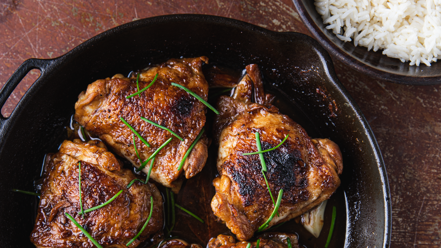 Chicken Adobo in a cast iron pan served next to white rice.