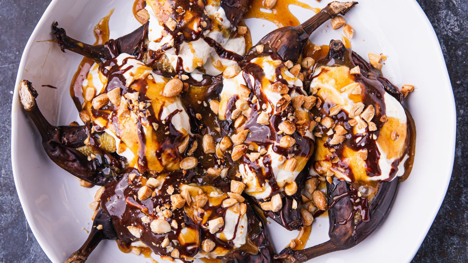 Bananas with chocolate and caramel drizzled over top on a plate
