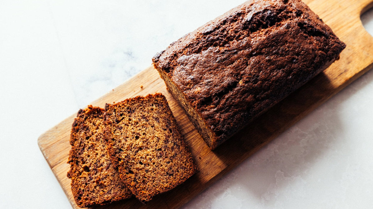 Wood-fired Banana Bread with two slices cut out on a board.